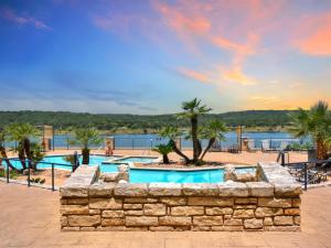 uma piscina de resort com uma parede de pedra e palmeiras em ILT 1223 Lakeside Escape em Lago Vista