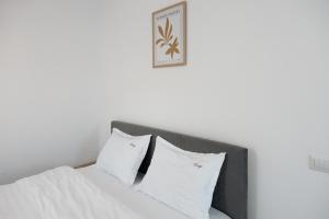 a bed with white pillows and a picture on the wall at Cozy ApartHotel Suceava in Suceava