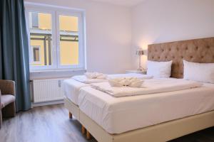 Schlafzimmer mit einem großen weißen Bett und einem Fenster in der Unterkunft H24 Factory Apartments Wolfsburg in Wolfsburg