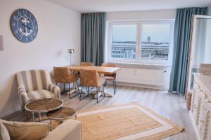 ein Wohnzimmer mit einem Tisch, Stühlen und einer Uhr in der Unterkunft H24 Factory Apartments Wolfsburg in Wolfsburg