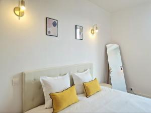 a bedroom with a white bed with yellow pillows at L'Étape Pisciacaise / F2 4pers. de standing in Poissy +11 photos