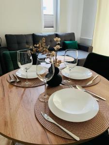 a wooden table with plates and wine glasses on it at MHL Apartament Lublin in Lublin