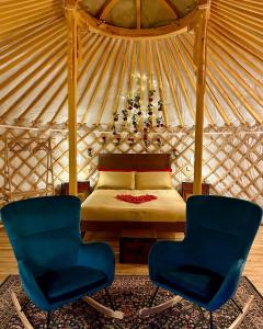 a bedroom with a bed in a yurt with two chairs at Glamping Il Rifugio dei Marsi in Ascoli Piceno