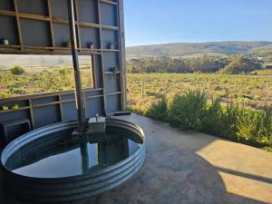 a building with a tub with a view of a field at Slow Track Farm in Baardskeerdersbos