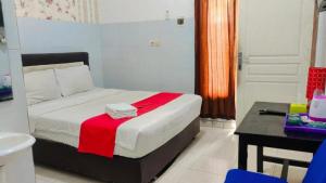 - une chambre avec un lit et une couverture rouge dans l'établissement RedDoorz near RSUD Nganjuk, à Nganjuk