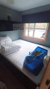 una bolsa azul sentada en una cama con una ventana en Cabin with a lake, en Sandnes