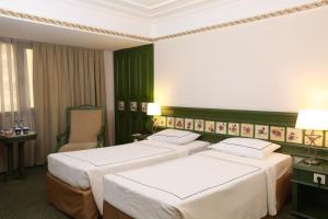 two beds in a hotel room with green walls at Anemon Hotel Izmir in Izmir