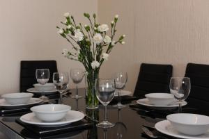 a table with glasses and a vase of white flowers at Dartside 1 in Dartmouth
