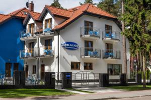 duży biały budynek z niebieskimi balkonami w obiekcie VivaLaMer w Pobierowie