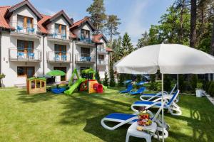 un patio con sillas y sombrilla y un edificio en VivaLaMer, en Pobierowo