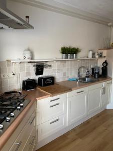 Una cocina con gabinetes blancos y un fregadero. en Kromme weele 26, en Middelburg 17 fotos más