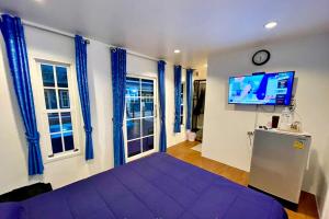 - une chambre avec un lit violet et une télévision à écran plat dans l'établissement Bluvilla Sattahip, à Sattahip