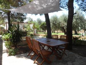 a wooden table and chairs in a yard with trees at B&B Santa Venardia in Gallipoli