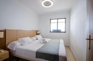 a bedroom with a bed with white sheets and a window at GEMELOS 10 Levante Beach in Benidorm