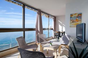 - un salon avec une table, des chaises et une grande fenêtre dans l'établissement GEMELOS 10 Levante Beach, à Benidorm