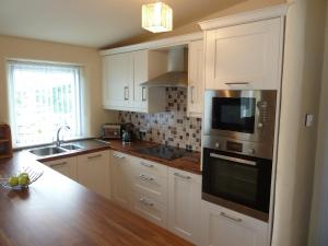a kitchen with white cabinets and a sink and a microwave at Gorse Hill Farm in Newcastle +24 photos