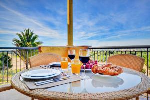 una mesa con 2 copas de vino y comida en el balcón en Vilamoura Prime @ The Residences at Victoria, en Quarteira