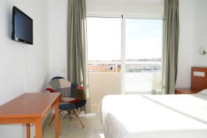 a hotel room with a desk and a bed and a window at Hotel Mirablau in Aguadulce