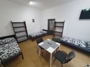 Cette chambre comprend 3 lits, une table et des chaises. dans l'établissement Ubytovna Moravan Brno, à Brno