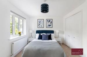 a white bedroom with a large bed and two windows at Guildford - 3 Bedroom Home - Driveway & Garden in Guildford
