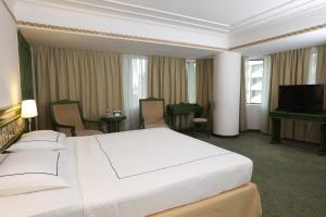 イズミールにあるアネモン ホテル イズミールの大型ベッドとテレビが備わるホテルルームです。