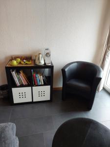 a black chair and a book shelf with books at BNB Les Prises in Les Ponts-de-Martel