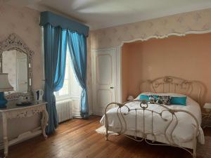 a bedroom with a bed with blue curtains and a mirror at Chateau De Mesnac, maison d hote et gites in Mesnac