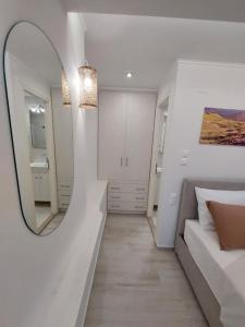 - une chambre blanche avec un miroir et un lit dans l'établissement Helens Mountain House, à Samos