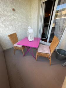 una mesa rosa y 2 sillas en un porche en En Provence chez Valérie en Cavaillon