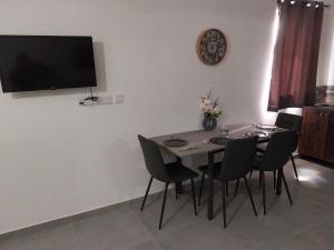 a dining room table with chairs and a television on a wall at St Gaetan Accomodation APT 7 B 