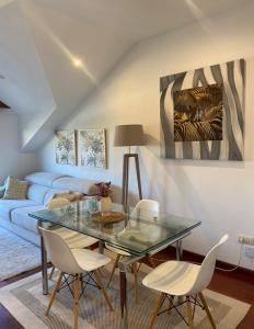sala de estar con mesa de cristal y sillas blancas en Acogedor atico en Ramallosa, en Pontevedra
