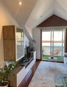 sala de estar con TV y ventana grande en Acogedor atico en Ramallosa, en Pontevedra