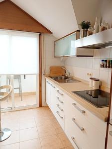 cocina con armarios blancos, fregadero y ventana en Acogedor atico en Ramallosa, en Pontevedra