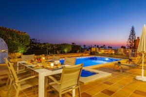 Un patio con mesa y sillas junto a una piscina. en Villa Florença by Algarve Vacation, en Albufeira
