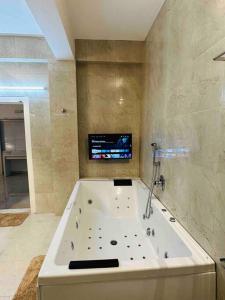 y baño con bañera grande y TV. en White House Sky View Theatre Villa in Gachibowli en Hyderabad