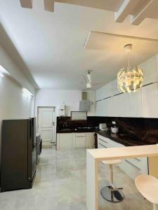 a kitchen with a black refrigerator and white cabinets at White House Sky View Theatre Villa in Gachibowli in Hyderabad