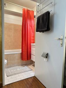 a bathroom with a shower with a red shower curtain at Très beau studio proche de Disneyland et de Paris in Ozoir-la-Ferrière
