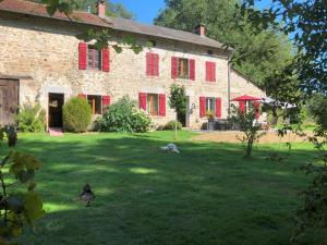 a large brick building with red shutters on a yard at Le Moulin de la Farge B&B in Saint-Moreil