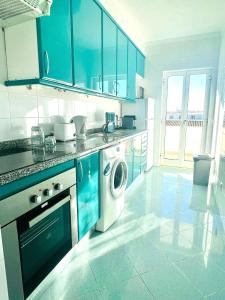 a kitchen with blue cabinets and a washing machine at Flat Luxuoso Praia da Oura in Albufeira