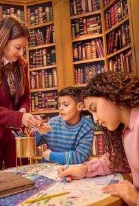Une femme et deux enfants regardent une carte dans une bibliothèque dans l'établissement Disneyland® Hotel, à Chessy