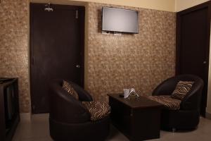 a room with two chairs and a television on a wall at HOTEL VARUNA Varanasi in Varanasi