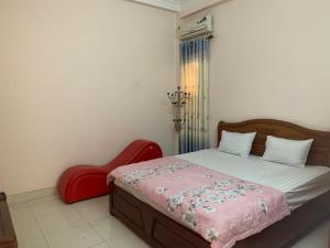 ein Schlafzimmer mit einem Bett und einem roten Stuhl in der Unterkunft Nhà Nghỉ Hải Nam in Dien Bien Phu
