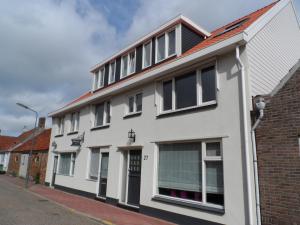 a white building with windows on a street at Riemens Residens in Zoutelande