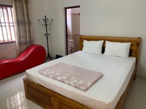 a bedroom with a bed and a red chair at Nhà Nghỉ Hải Nam in Dien Bien Phu