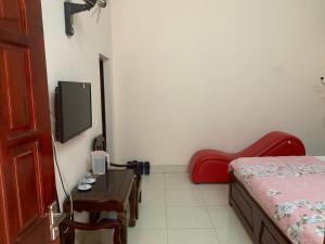 a bedroom with a bed and a table and a tv at Nhà Nghỉ Hải Nam in Dien Bien Phu