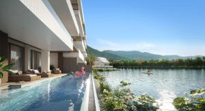 a swimming pool next to a house with a lake at Angsana Oceanview Residences by Laguna Phuket in Bang Tao Beach
