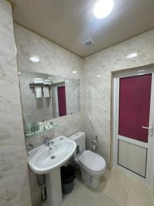 a bathroom with a white toilet and a sink at Hotel Sherdor in Samarkand
