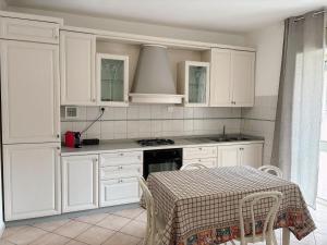 a kitchen with white cabinets and a table with chairs at Orchidea House in Serravalle Scrivia