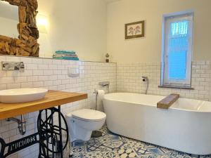 a bathroom with a tub and a toilet and a sink at Ferienhaus am Lebbiner Bodden in Neuenkirchen +16 photos