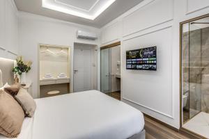 a white bedroom with a bed and a window at ATAROOMS Suites Napoli in Naples